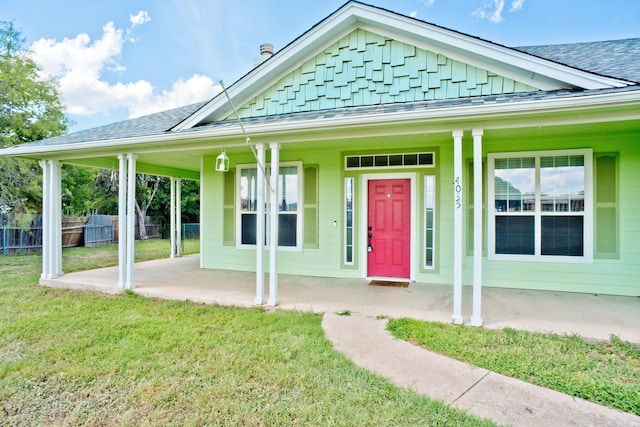 view of front of house with a shingled roof, board and batten siding, a front yard, and fence