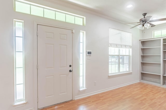 foyer entrance with light wood-style floors, crown molding, baseboards, and ceiling fan