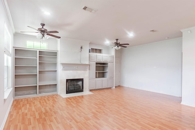 unfurnished living room featuring a fireplace with flush hearth, visible vents, ceiling fan, and crown molding