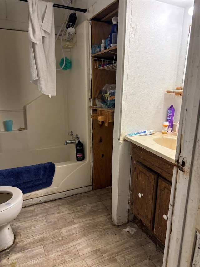 full bathroom with bathing tub / shower combination, toilet, vanity, and hardwood / wood-style flooring