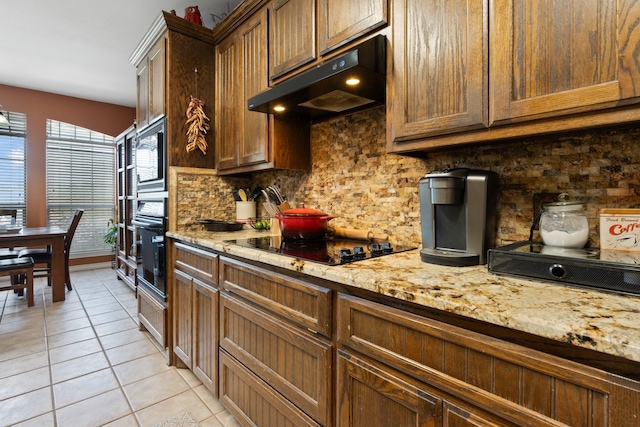 kitchen featuring tasteful backsplash, light stone counters, light tile patterned flooring, and black appliances