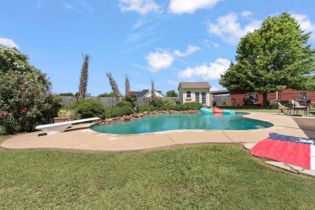 view of swimming pool featuring an outbuilding, a yard, a patio, and a diving board