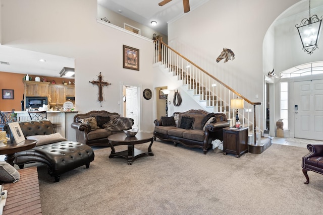 living room with ceiling fan, crown molding, a towering ceiling, and light carpet