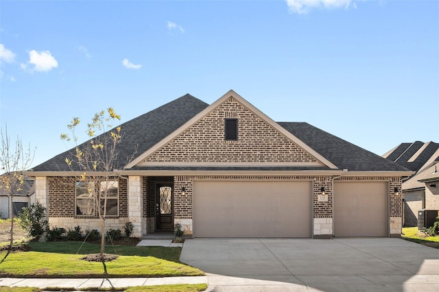 view of front of home with a front yard, central AC unit, and a garage