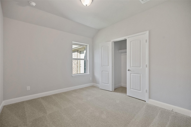 unfurnished bedroom featuring light colored carpet, a closet, and vaulted ceiling