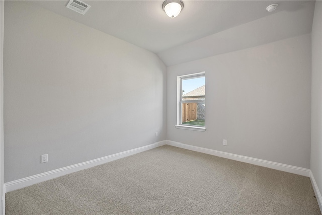 carpeted spare room featuring vaulted ceiling