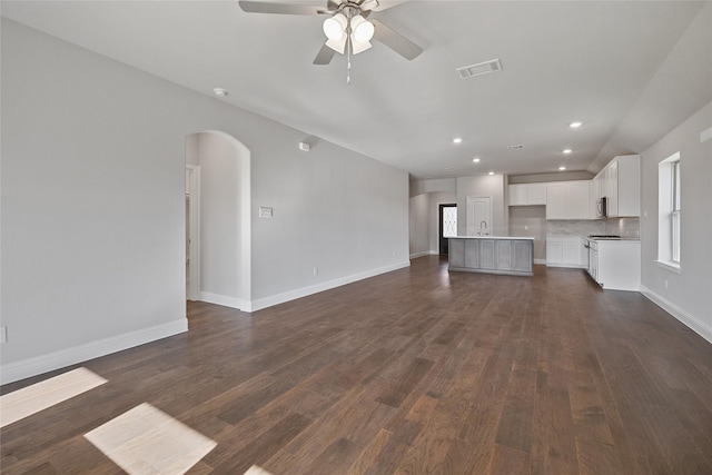 unfurnished living room featuring ceiling fan, dark hardwood / wood-style flooring, and sink