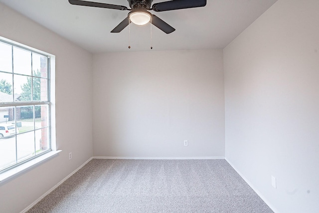 carpeted spare room featuring a wealth of natural light and ceiling fan