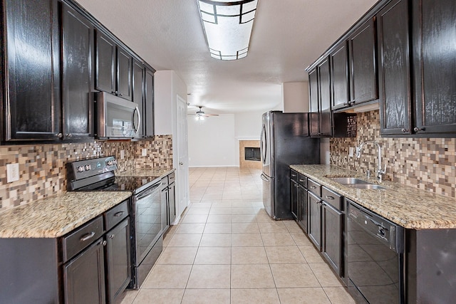 kitchen featuring light stone counters, sink, ceiling fan, and appliances with stainless steel finishes