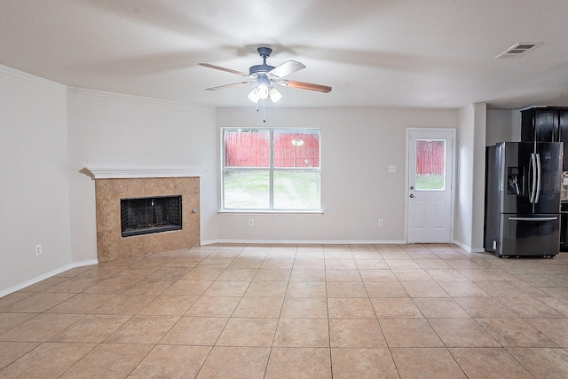 unfurnished living room featuring ceiling fan, a fireplace, light tile patterned floors, and ornamental molding