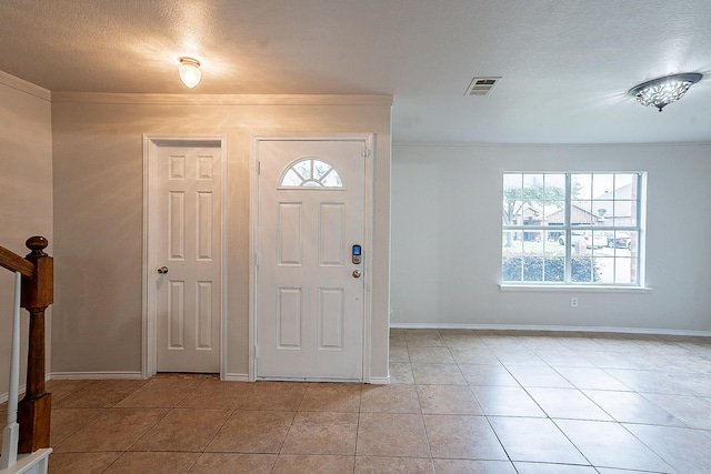 entrance foyer featuring light tile patterned floors, a textured ceiling, and ornamental molding