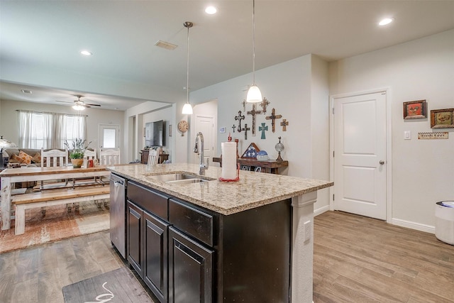 kitchen featuring stainless steel dishwasher, ceiling fan, sink, pendant lighting, and a center island with sink