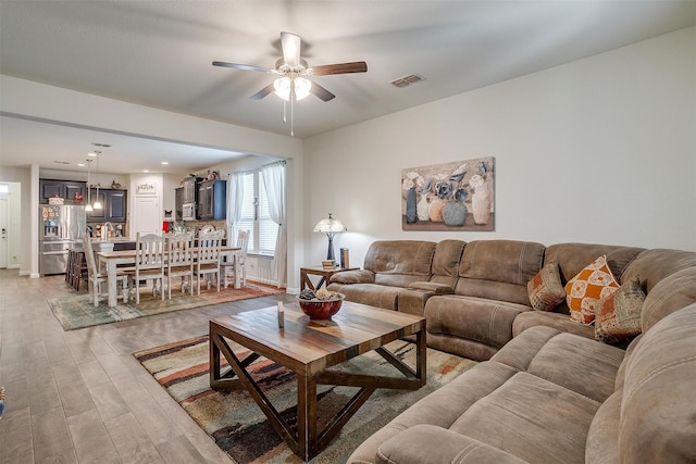 living room featuring light hardwood / wood-style flooring and ceiling fan