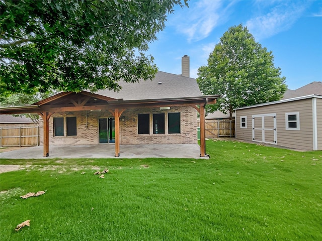 back of property with an outbuilding, a yard, and a patio