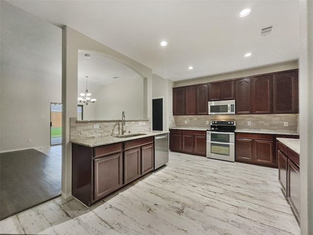 kitchen with pendant lighting, sink, appliances with stainless steel finishes, dark brown cabinetry, and light wood-type flooring