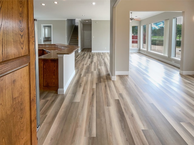 kitchen featuring ceiling fan, light wood-type flooring, and dark stone counters