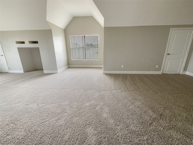 unfurnished living room featuring carpet floors and vaulted ceiling