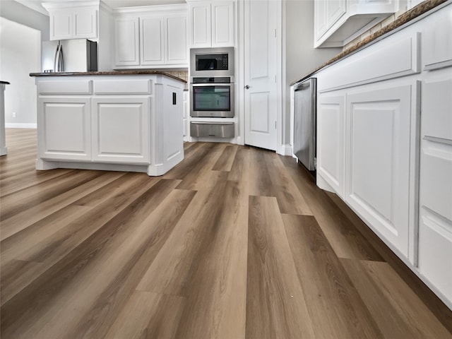 kitchen with appliances with stainless steel finishes, dark hardwood / wood-style floors, and white cabinetry