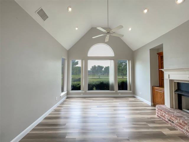 unfurnished living room featuring ceiling fan, light hardwood / wood-style floors, a fireplace, and a healthy amount of sunlight