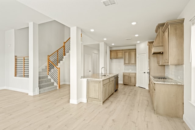 kitchen with tasteful backsplash, light stone countertops, sink, light wood-type flooring, and black electric cooktop