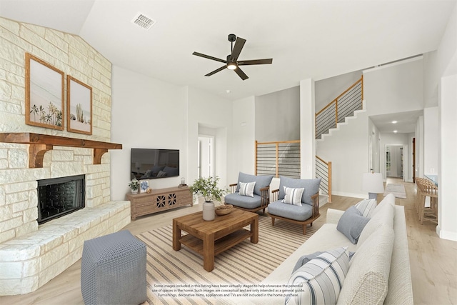 living room with ceiling fan, high vaulted ceiling, light wood-type flooring, and a fireplace