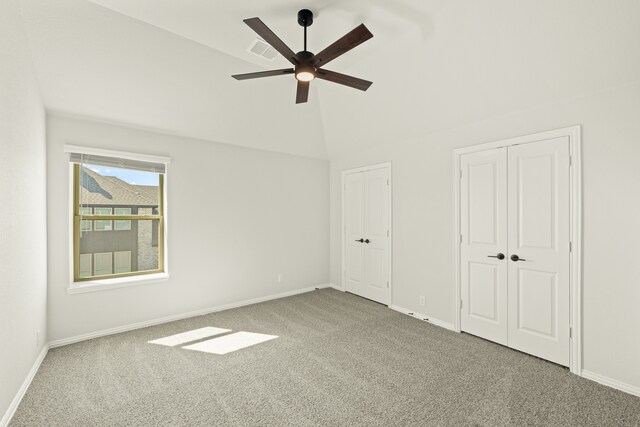 interior space with ceiling fan, carpet, lofted ceiling, and two closets