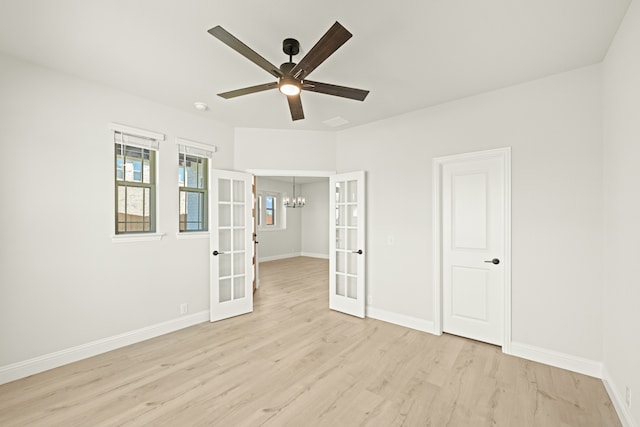 spare room with french doors, light hardwood / wood-style flooring, and ceiling fan with notable chandelier