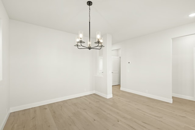 unfurnished room featuring light hardwood / wood-style flooring and a notable chandelier