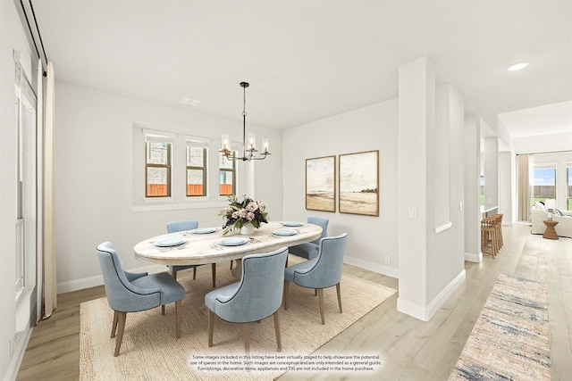 dining area with light hardwood / wood-style flooring and a notable chandelier