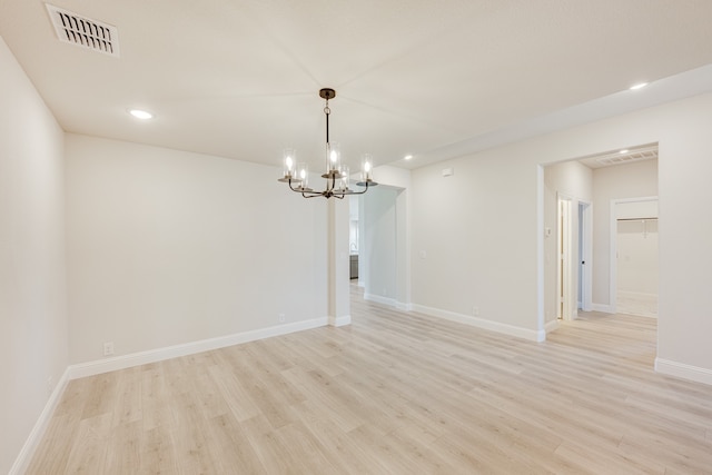 unfurnished room with a notable chandelier and light hardwood / wood-style flooring