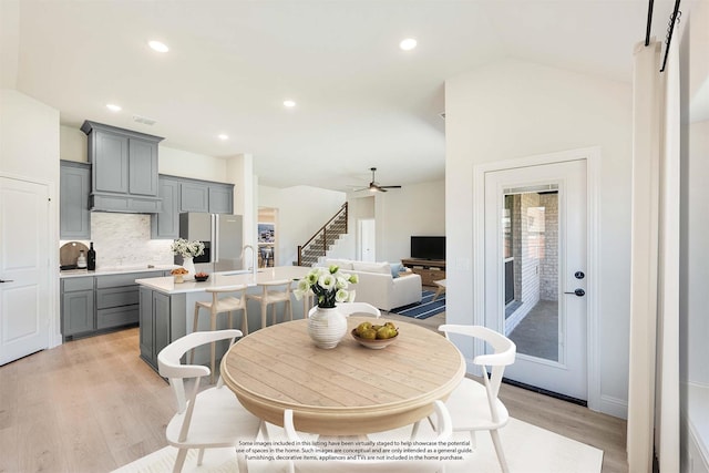 dining space with ceiling fan, vaulted ceiling, and light wood-type flooring