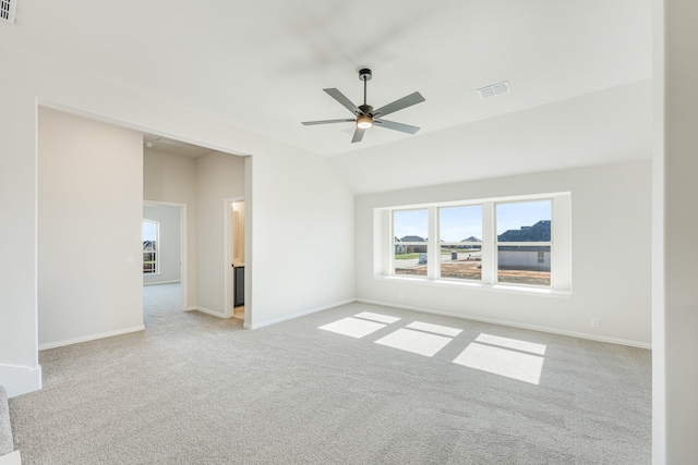 spare room with light carpet, vaulted ceiling, and ceiling fan