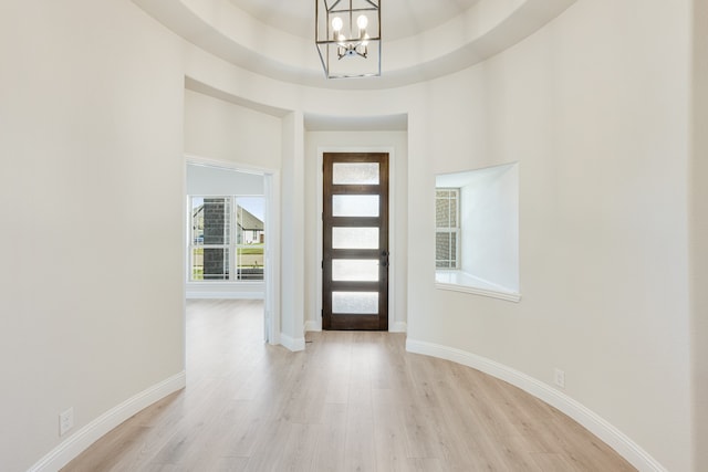 entryway featuring light hardwood / wood-style floors, an inviting chandelier, and a tray ceiling