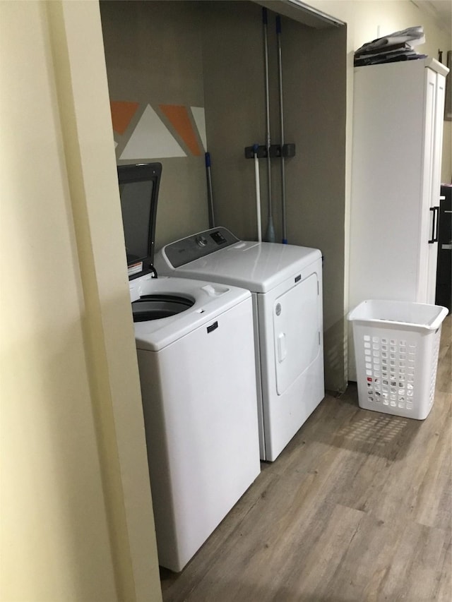 laundry room featuring washer and clothes dryer and light hardwood / wood-style flooring