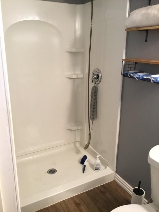 bathroom featuring hardwood / wood-style flooring, toilet, and walk in shower