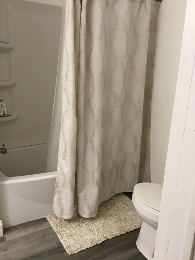 bathroom featuring wood-type flooring, toilet, and shower / bathtub combination with curtain