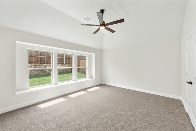 empty room with vaulted ceiling, ceiling fan, and carpet flooring