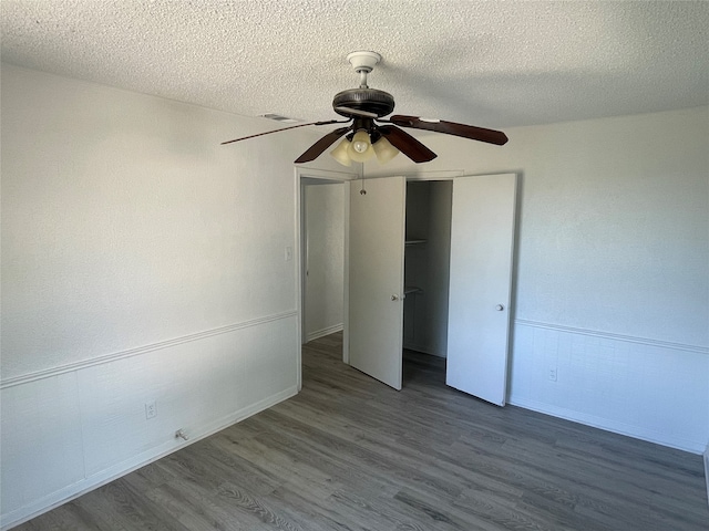 unfurnished bedroom featuring ceiling fan, a textured ceiling, a closet, and hardwood / wood-style floors