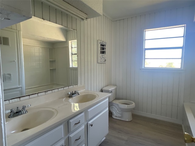 bathroom with vanity, a bathtub, wood walls, wood-type flooring, and toilet