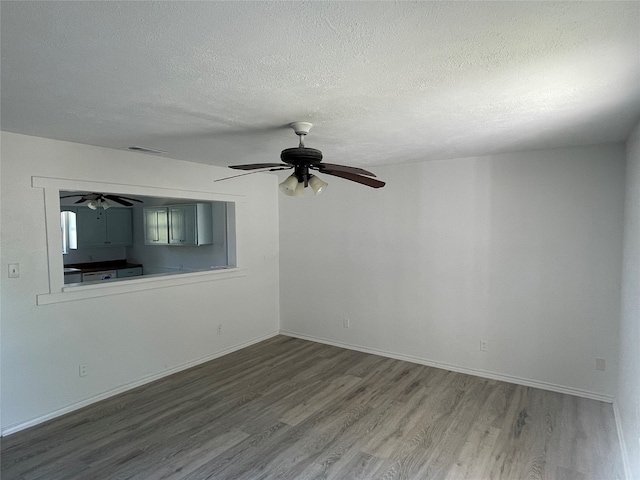 empty room with ceiling fan, hardwood / wood-style flooring, and a textured ceiling