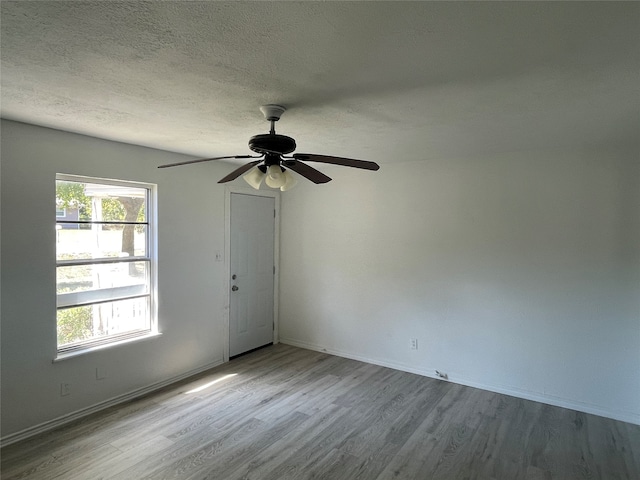 spare room with a textured ceiling, light hardwood / wood-style floors, and ceiling fan