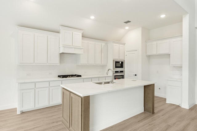 kitchen featuring white cabinetry, sink, stainless steel appliances, an island with sink, and light wood-type flooring