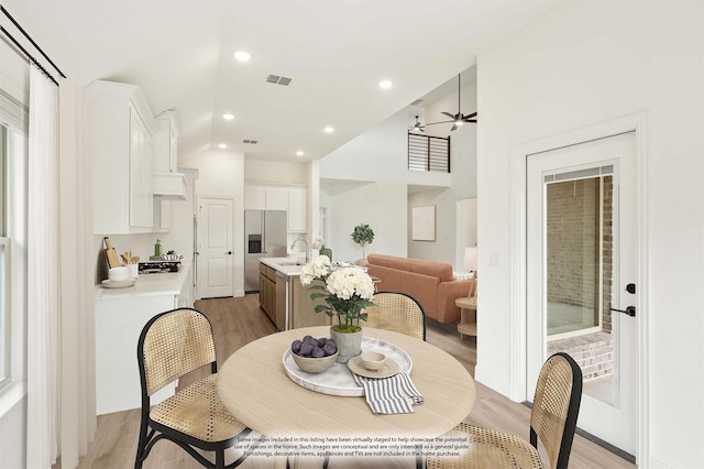 dining space with ceiling fan, light hardwood / wood-style floors, and sink