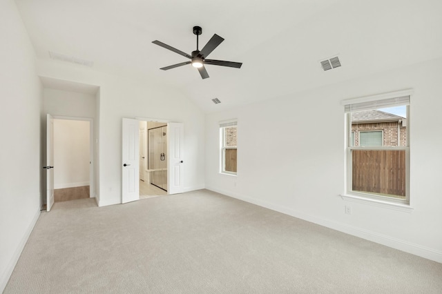 unfurnished bedroom featuring ceiling fan, light carpet, connected bathroom, and multiple windows