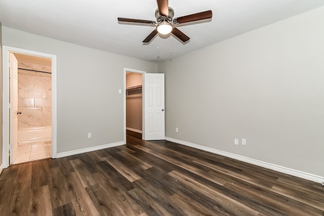 unfurnished bedroom with a walk in closet, dark hardwood / wood-style floors, ceiling fan, and ensuite bath