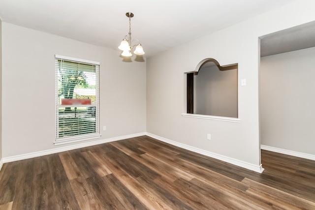 empty room featuring dark wood-type flooring and an inviting chandelier