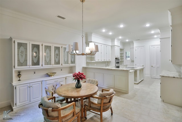 tiled dining room with a notable chandelier, ornamental molding, and sink