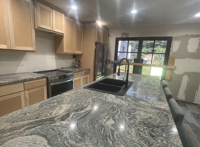 kitchen featuring freestanding refrigerator, recessed lighting, dark stone counters, stainless steel electric stove, and a sink