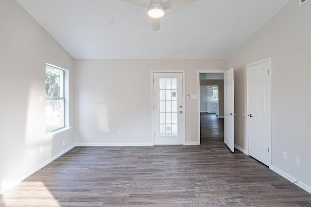 empty room featuring a healthy amount of sunlight, dark wood-type flooring, ceiling fan, and lofted ceiling