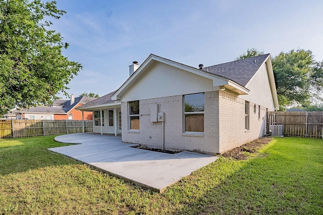 back of house with cooling unit, a patio area, and a lawn